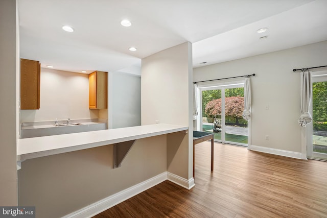 12213 Lake Potomac Ter, Potomac, MD 20854 - kitchen featuring baseboards, wood finished floors, recessed lighting, a kitchen bar, and light countertops