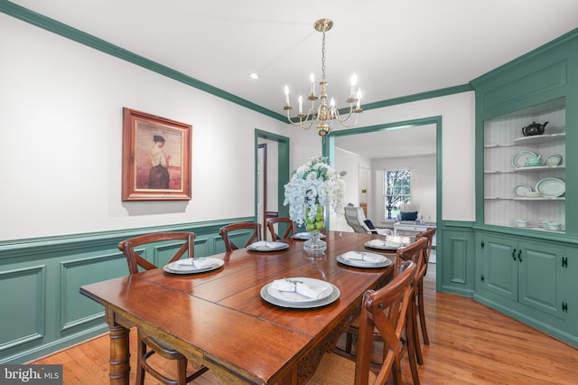 13423 Rippling Brook Dr, Silver Spring, MD 20906 - dining room featuring a chandelier, ornamental molding, light wood finished floors, built in shelves, and wainscoting