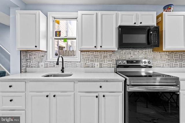 3559 4th St, Baltimore, MD 21225 - kitchen featuring black microwave, stainless steel range with electric stovetop, a sink, white cabinetry, and backsplash