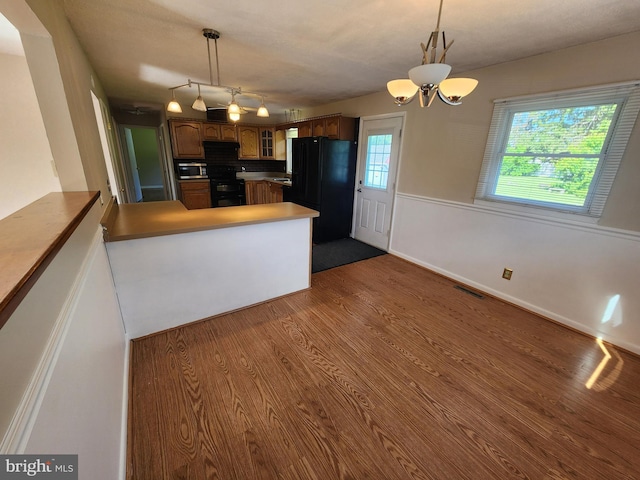 1983 Nault Rd, Dover, DE 19904 - kitchen with black appliances, glass insert cabinets, dark wood-style floors, a peninsula, and a chandelier