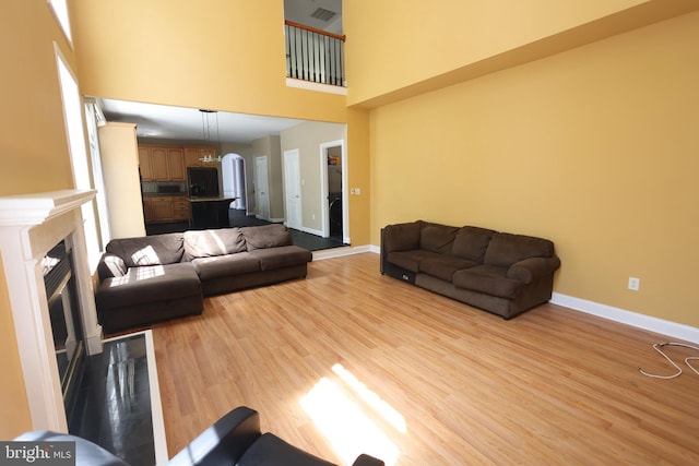 14714 Mount Calvert Rd, Upper Marlboro, MD 20772 - living area with a high ceiling, baseboards, light wood finished floors, and a glass covered fireplace