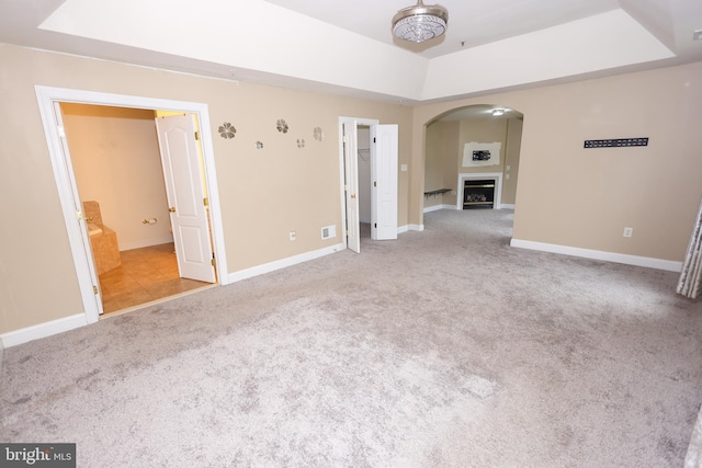 14714 Mount Calvert Rd, Upper Marlboro, MD 20772 - unfurnished room featuring a tray ceiling, carpet, arched walkways, baseboards, and a fireplace