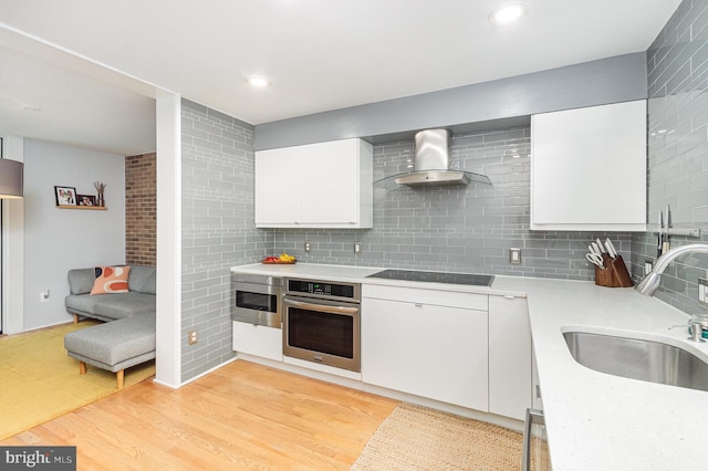 1690 Chimney House Rd, Reston, VA 20190 - kitchen with stainless steel appliances, wall chimney exhaust hood, light countertops, white cabinetry, and backsplash