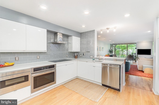 1690 Chimney House Rd, Reston, VA 20190 - kitchen featuring stainless steel appliances, wall chimney exhaust hood, light wood-style floors, tasteful backsplash, and recessed lighting