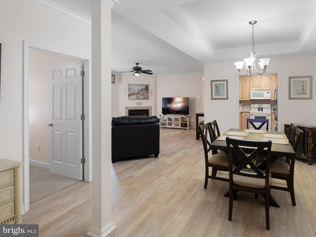 30619 Cedar Neck Rd Unit 1101, Ocean View, DE 19970 - dining space featuring light wood-type flooring, a tiled fireplace, ceiling fan, a tray ceiling, and a chandelier