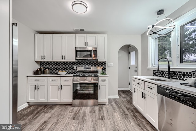 6505 Corkley Rd, Baltimore, MD 21237 - kitchen with stainless steel appliances, a sink, arched walkways, decorative backsplash, and baseboards