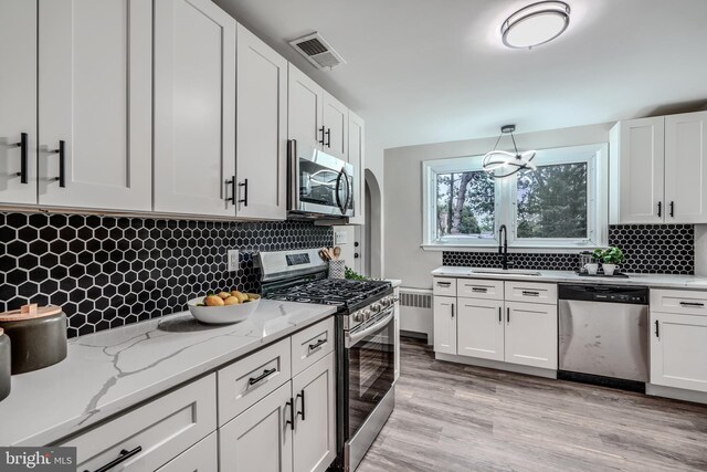 6505 Corkley Rd, Baltimore, MD 21237 - kitchen featuring stainless steel appliances, a sink, radiator heating unit, decorative backsplash, and white cabinets