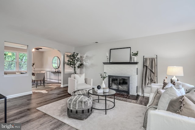 6505 Corkley Rd, Baltimore, MD 21237 - living area featuring arched walkways, wood finished floors, a brick fireplace, and baseboards