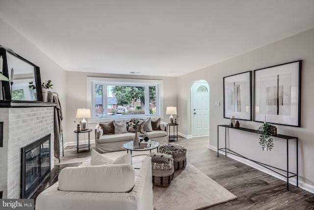 6505 Corkley Rd, Baltimore, MD 21237 - living room with arched walkways, wood finished floors, a fireplace, and baseboards