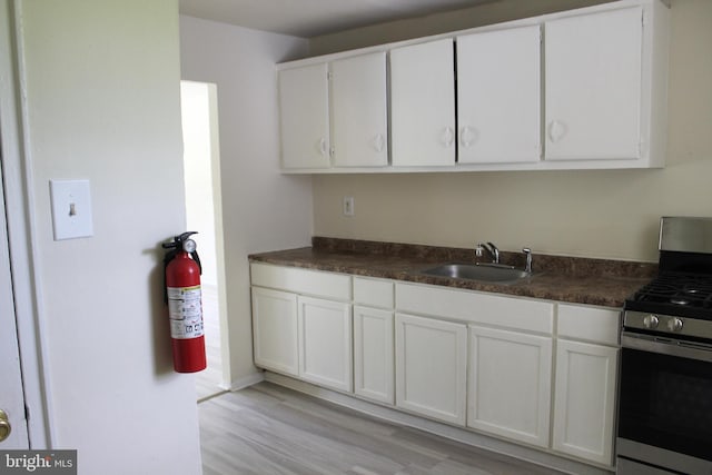 199 Kinsley Rd, Pemberton, NJ 08068 - kitchen featuring stainless steel gas range oven, a sink, dark countertops, white cabinetry, and light wood-style flooring
