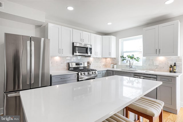 2220 13th St NE, Washington, DC 20018 - kitchen featuring appliances with stainless steel finishes, a sink, a kitchen bar, recessed lighting, and light countertops