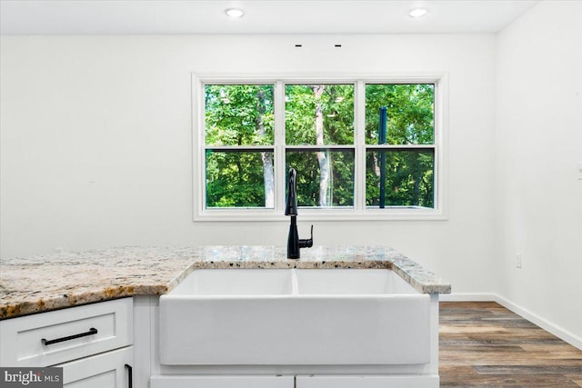 163 Hyde Park Ln, Charles Town, WV 25414 - kitchen view of a sink, wood finished floors, white cabinets, baseboards, and light stone counters