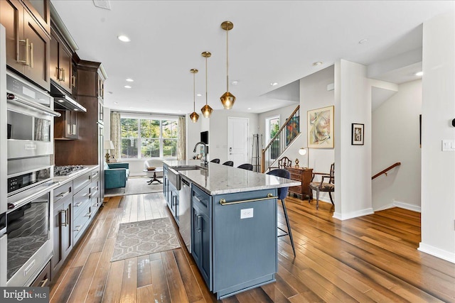 368 Star Tavern Ln, West Chester, PA 19382 - kitchen featuring dark wood-style floors, a kitchen breakfast bar, a center island with sink, baseboards, and light stone countertops