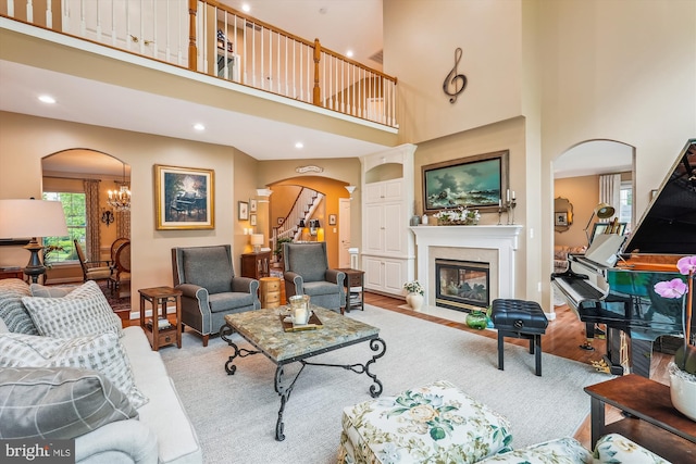18403 Rim Rock Cir, Leesburg, VA 20176 - living room featuring arched walkways, light wood-style floors, a high ceiling, a fireplace with flush hearth, and recessed lighting