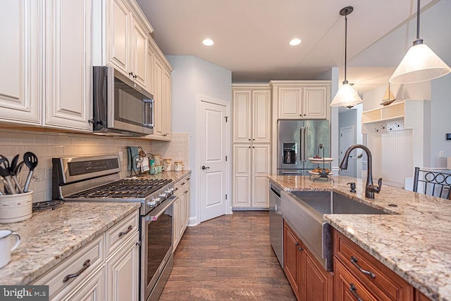24440 Harvest Cir, Milton, DE 19968 - kitchen featuring appliances with stainless steel finishes, a sink, dark wood-style floors, hanging light fixtures, and light stone countertops