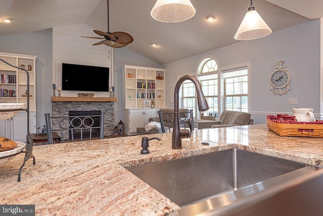 24440 Harvest Cir, Milton, DE 19968 - kitchen featuring a sink, vaulted ceiling, a ceiling fan, a stone fireplace, and light stone countertops