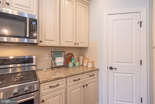24440 Harvest Cir, Milton, DE 19968 - kitchen featuring stainless steel appliances, cream cabinets, backsplash, and light stone counters