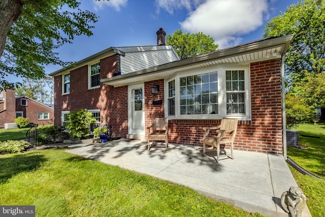 105 Lombardy Dr, Wallingford, PA 19086 - rear view of property featuring brick siding, a lawn, a chimney, and a patio