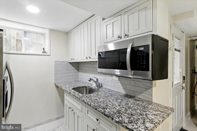 1209 Chapel Oaks Dr, Capitol Heights, MD 20743 - kitchen with stainless steel appliances, a sink, baseboards, light marble finish flooring, and light stone countertops