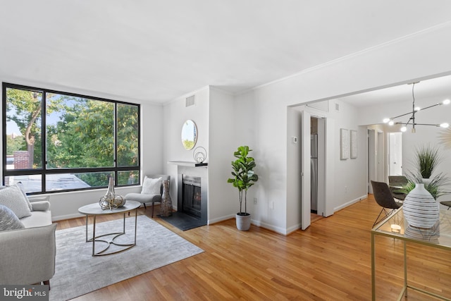 2605 39th St NW Unit 303, Washington, DC 20007 - living area with light wood-style floors, a fireplace with flush hearth, baseboards, a chandelier, and ornamental molding