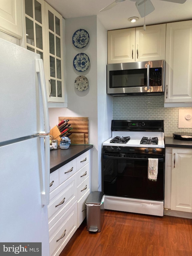 3900 Tunlaw Rd NW Unit 419, Washington, DC 20007 - kitchen with freestanding refrigerator, stainless steel microwave, black gas stove, dark countertops, and decorative backsplash