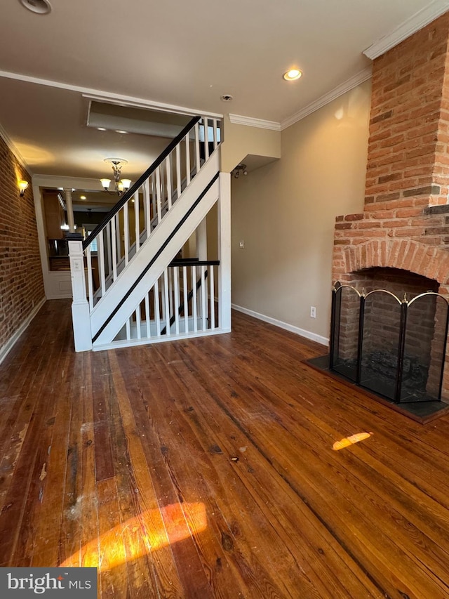 1406 Clarkson St, Baltimore, MD 21230 - unfurnished living room with stairway, wood-type flooring, crown molding, a brick fireplace, and brick wall
