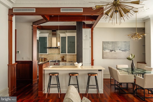 1830 Rittenhouse Sq Unit 11C, Philadelphia, PA 19103 - kitchen with a chandelier, wall chimney exhaust hood, a breakfast bar area, decorative backsplash, and dark wood-style floors