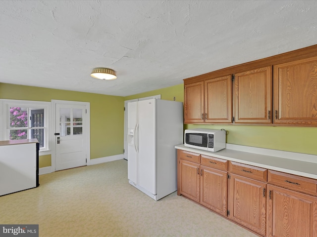 2240 Mahantongo St, Pottsville, PA 17901 - kitchen featuring white appliances, light countertops, brown cabinetry, a textured ceiling, and baseboards