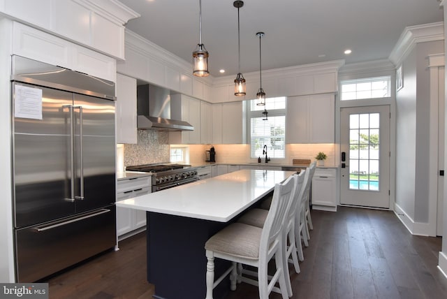 3 Laurel St, Rehoboth Beach, DE 19971 - kitchen featuring high end appliances, wall chimney range hood, a sink, light countertops, and dark wood-style flooring