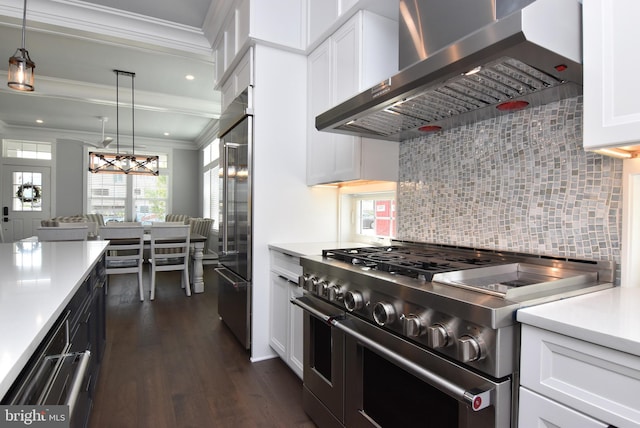 3 Laurel St, Rehoboth Beach, DE 19971 - kitchen featuring high end appliances, wall chimney range hood, crown molding, dark wood-type flooring, and light countertops
