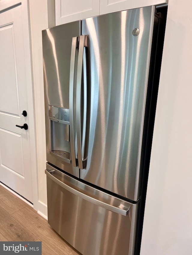 34232 Brenner Ln, Lewes, DE 19958 - detailed view of stainless steel refrigerator with ice dispenser, light wood finished floors, and white cabinetry
