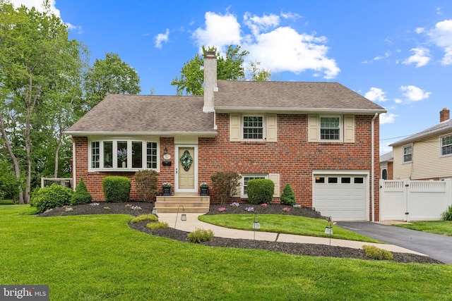 622 Hutchinson Ter, Holmes, PA 19043 - split level home featuring asphalt driveway, a garage, a chimney, brick siding, and roof with shingles