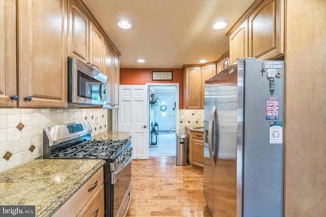 622 Hutchinson Ter, Holmes, PA 19043 - kitchen featuring appliances with stainless steel finishes, light wood finished floors, light stone counters, recessed lighting, and decorative backsplash