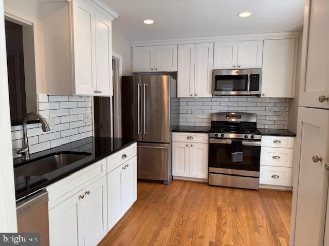 10024 Park Woods Ln, Burke, VA 22015 - kitchen featuring appliances with stainless steel finishes, dark countertops, a sink, white cabinets, and recessed lighting