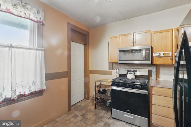 2530 Arunah Ave, Baltimore, MD 21216 - kitchen featuring stainless steel appliances, light brown cabinetry, stone finish flooring, light countertops, and decorative backsplash