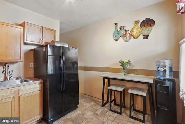 2530 Arunah Ave, Baltimore, MD 21216 - kitchen featuring freestanding refrigerator, a sink, stone finish flooring, backsplash, and light countertops