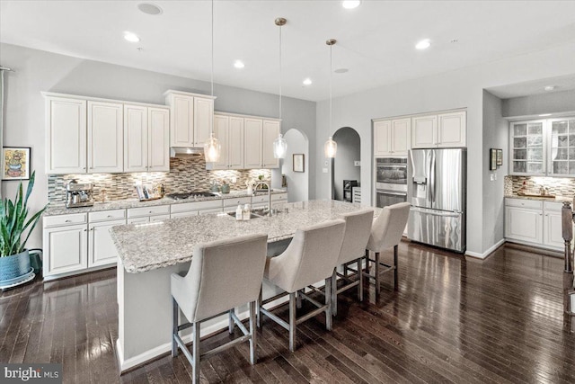 6808 Rehnquist Ct, New Market, MD 21774 - kitchen featuring appliances with stainless steel finishes, arched walkways, decorative backsplash, a sink, and dark wood-style flooring