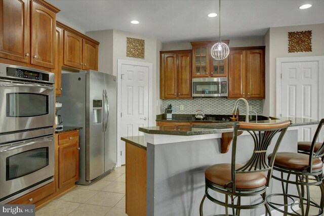 11516 Mystic Rock Ln N, Waynesboro, PA 17268 - kitchen featuring stainless steel appliances, decorative backsplash, a breakfast bar area, brown cabinets, and recessed lighting