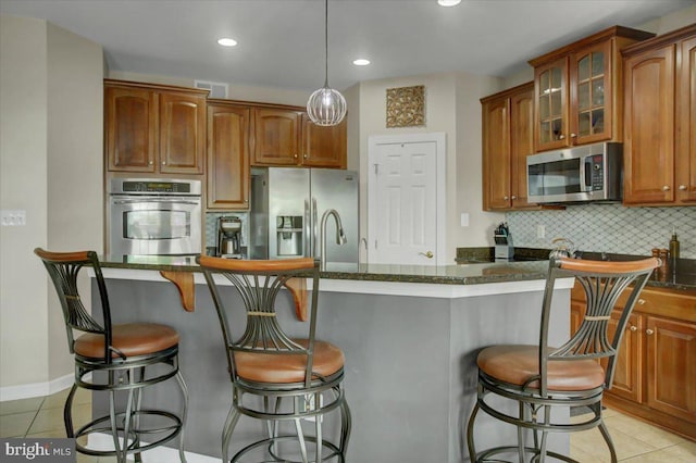 11516 Mystic Rock Ln N, Waynesboro, PA 17268 - kitchen with stainless steel appliances, light tile patterned floors, backsplash, glass insert cabinets, and a kitchen bar