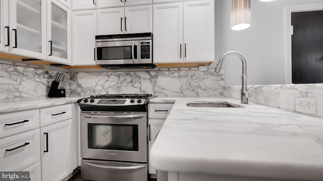 1323 Clifton St NW Unit 34, Washington, DC 20009 - kitchen with stainless steel appliances, white cabinetry, light stone counters, and glass insert cabinets