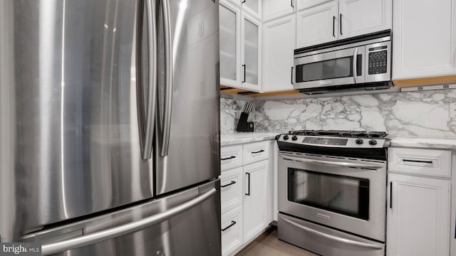 1323 Clifton St NW Unit 34, Washington, DC 20009 - kitchen with appliances with stainless steel finishes, white cabinetry, light stone counters, and decorative backsplash