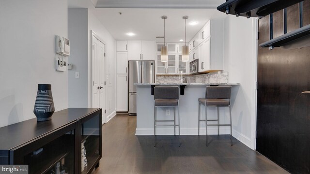 1323 Clifton St NW Unit 34, Washington, DC 20009 - kitchen with stainless steel appliances, white cabinetry, glass insert cabinets, a breakfast bar, and backsplash