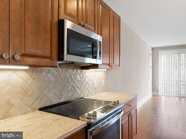 105 Sutton Way, Newark, DE 19711 - kitchen featuring appliances with stainless steel finishes, baseboards, tasteful backsplash, wood finished floors, and brown cabinetry