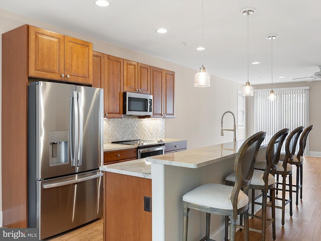 105 Sutton Way, Newark, DE 19711 - kitchen featuring appliances with stainless steel finishes, light wood-style floors, backsplash, a center island with sink, and recessed lighting