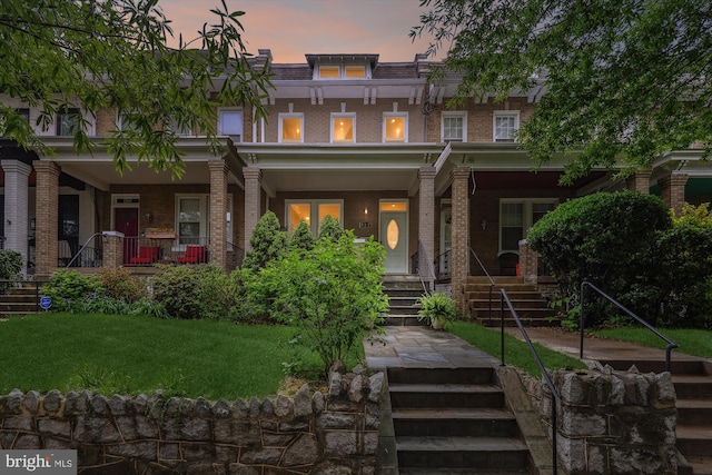 422 Hamilton St NW, Washington, DC 20011 - view of front of property with covered porch, brick siding, a lawn, and stairs
