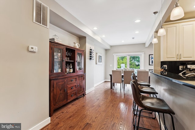 422 Hamilton St NW, Washington, DC 20011 - kitchen with baseboards, a breakfast bar, wood finished floors, dark countertops, and decorative light fixtures