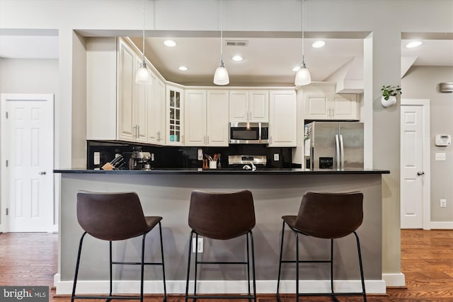 422 Hamilton St NW, Washington, DC 20011 - kitchen with appliances with stainless steel finishes, dark countertops, a breakfast bar area, decorative backsplash, and glass insert cabinets