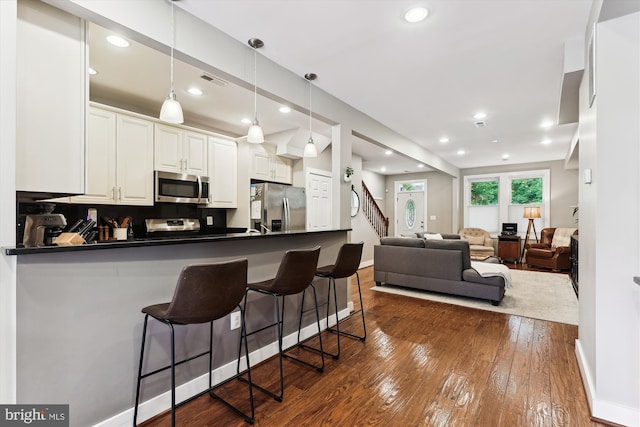 422 Hamilton St NW, Washington, DC 20011 - kitchen featuring appliances with stainless steel finishes, dark countertops, a kitchen breakfast bar, dark wood-style flooring, and recessed lighting
