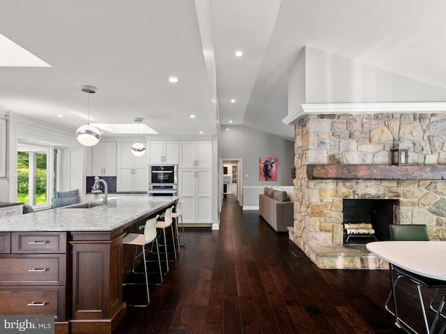 2762 Horseshoe Trl, Chester Springs, PA 19425 - kitchen featuring white cabinetry, a fireplace, dark wood-style flooring, a breakfast bar, and lofted ceiling