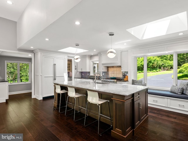 2762 Horseshoe Trl, Chester Springs, PA 19425 - kitchen featuring a skylight, light stone counters, decorative backsplash, white cabinets, and dark wood finished floors